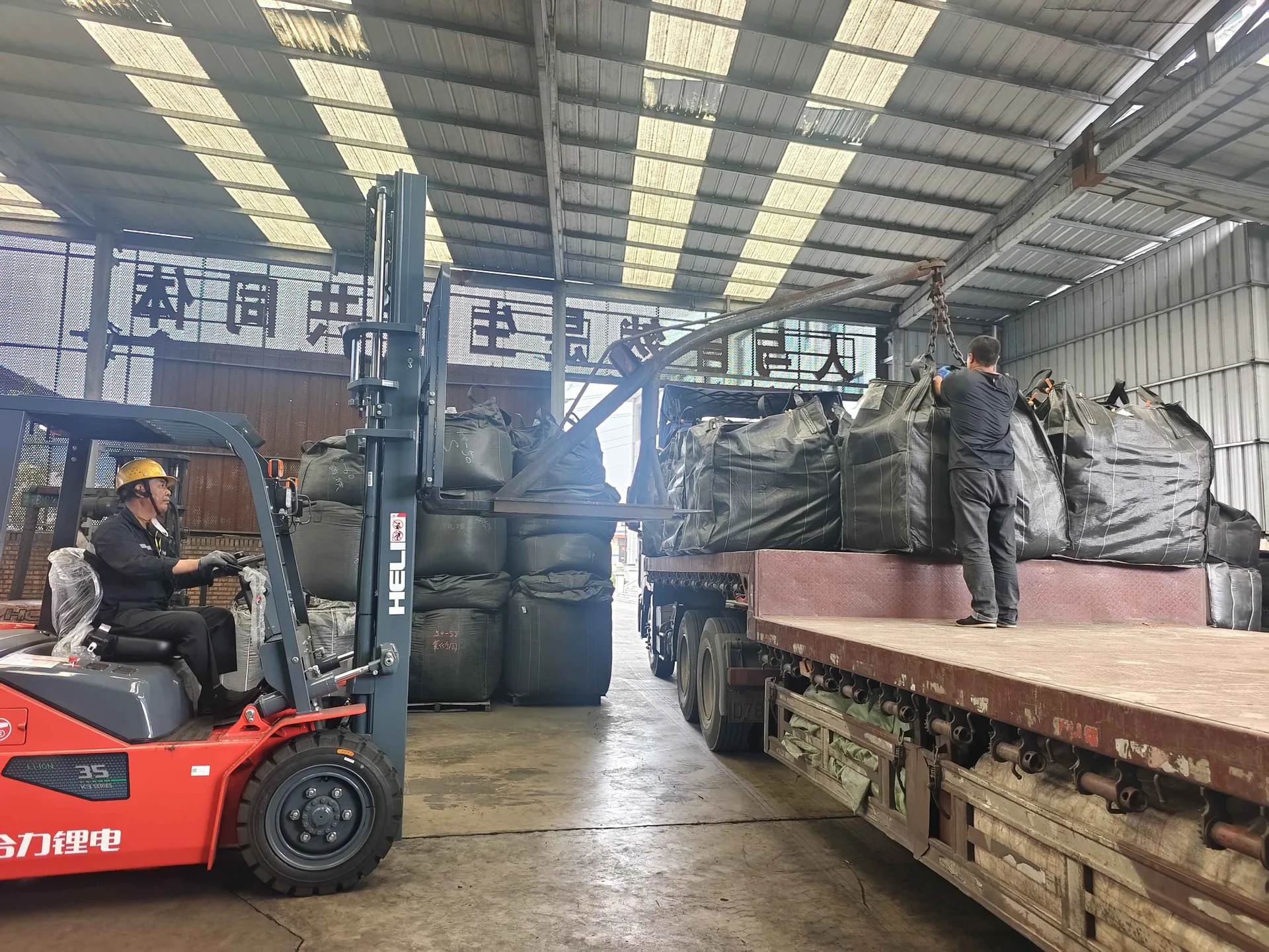 Ein Gabelstapler lädt Big Bags mit Aktivkohle auf einen Lkw im Werk in Qizhong